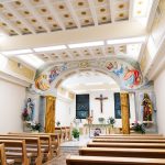Interior of a bright, decorated church with pews and religious statues.