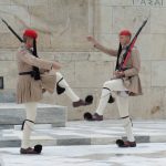 Two ceremonial guards in traditional uniforms performing a synchronized dance.