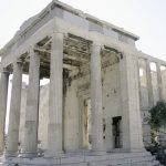 Ancient Greek temple ruins with tall columns and white stone.