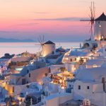 Sunset view of white buildings and windmills in Santorini, Greece.