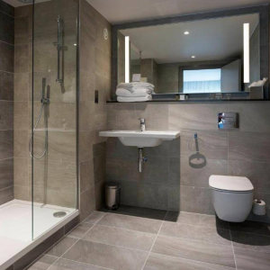 Modern bathroom with glass shower, floating sink, and wall-mounted toilet.