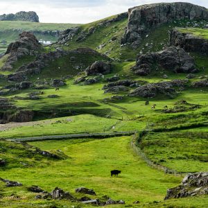 Lush green hills with rocky outcrops under a cloudy sky.